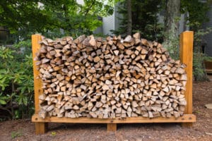 A neatly stacked woodpile in a wooden rack. The wood is cut into logs and appears to be dry.