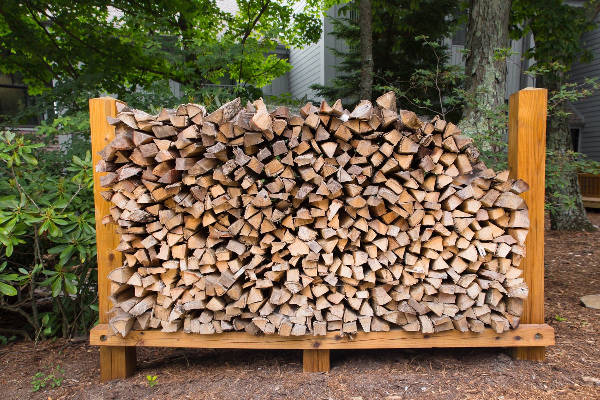 A neatly stacked woodpile in a wooden rack. The wood is cut into logs and appears to be dry.