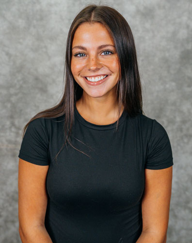 A young woman with long dark hair wearing a black t-shirt. She is smiling and looking at the camera.