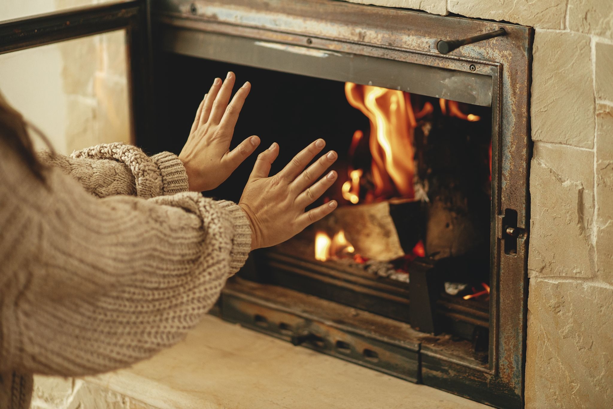 Woman warming her hands by the fire. A cozy scene with a fireplace.