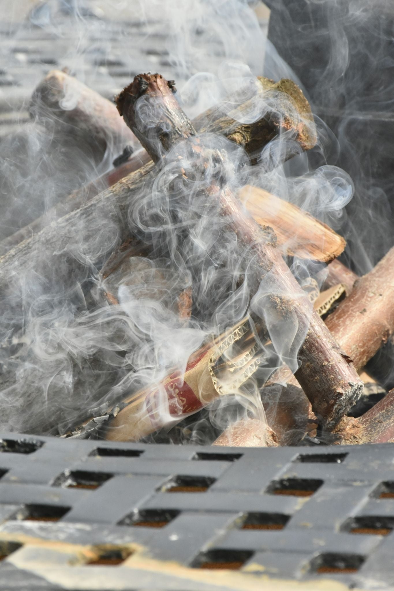 Smoke rising from burning wood logs. A pile of smoldering wood.