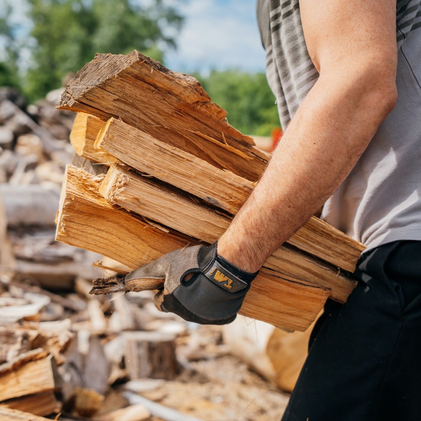 Man carrying firewood. He is wearing gloves.